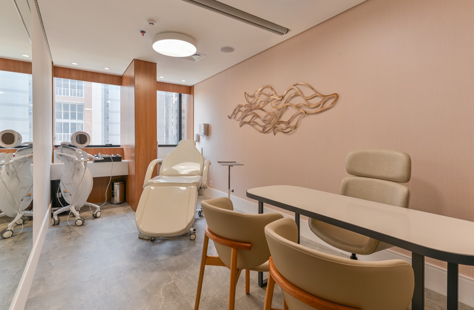 Sala de procedimentos com maca reclinável e cadeiras claras
